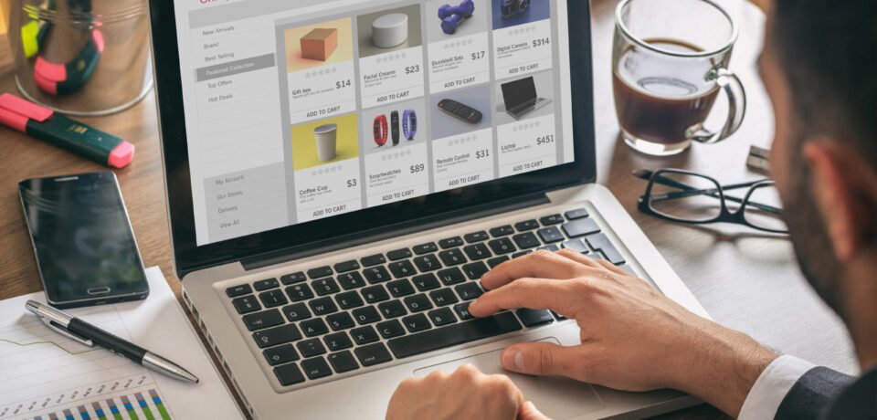 Online shop website developer, Man working with a computer laptop, eshop web page on the screen, office desk background.