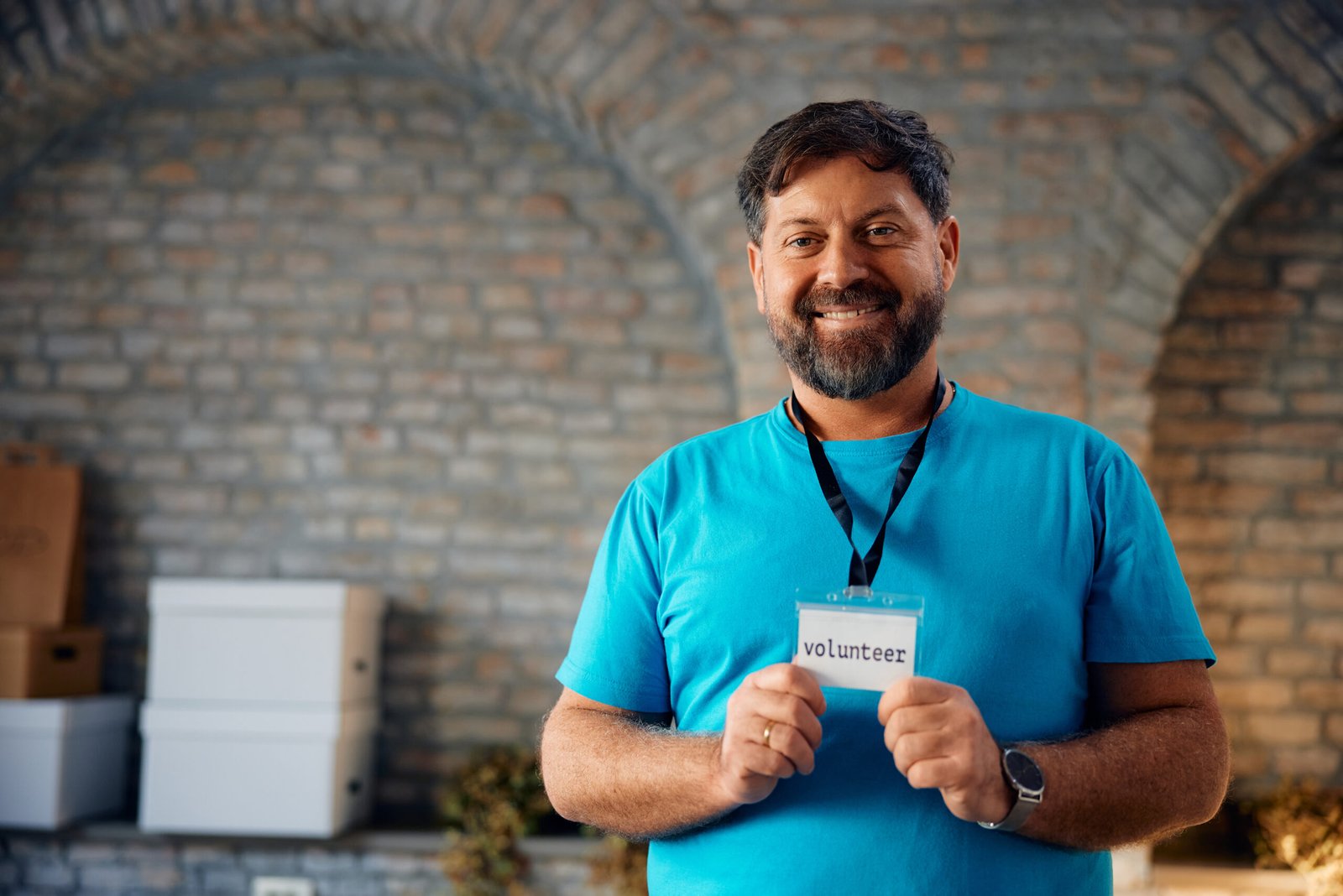 Happy man holding his volunteer identification card and looking at camera. Copy space.