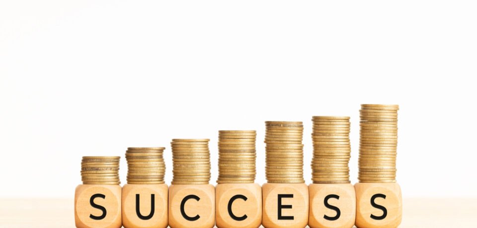 Success concept. Wooden blocks with text and rising stacked coins. Copy space