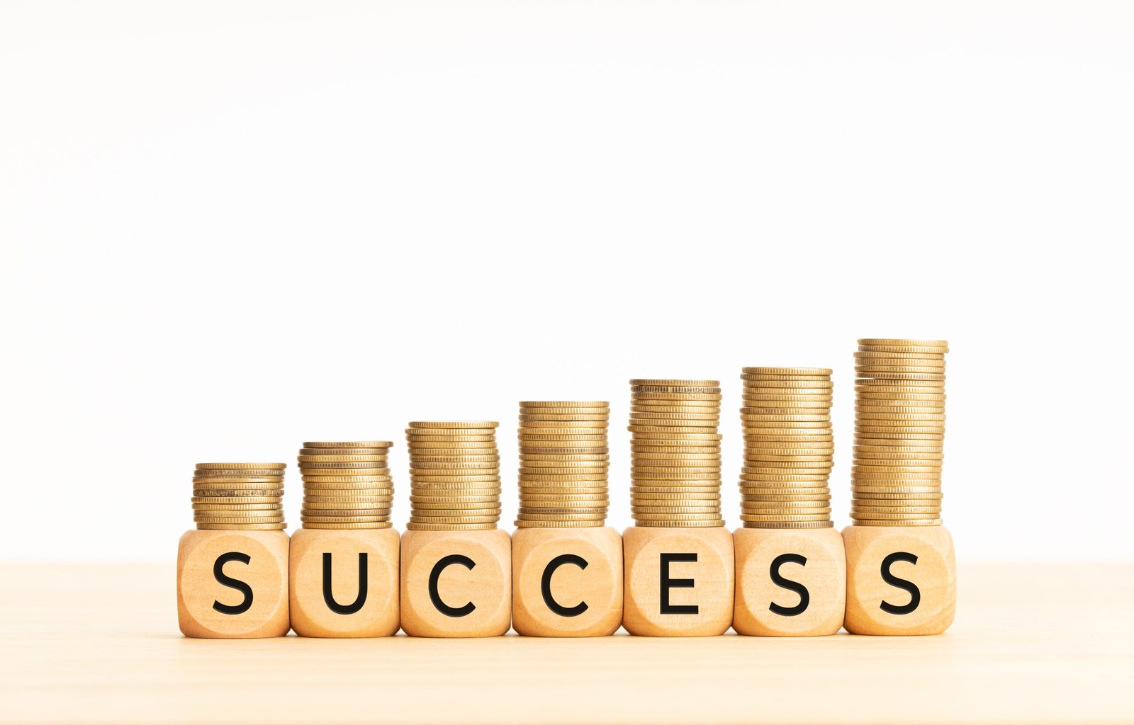 Success concept. Wooden blocks with text and rising stacked coins. Copy space