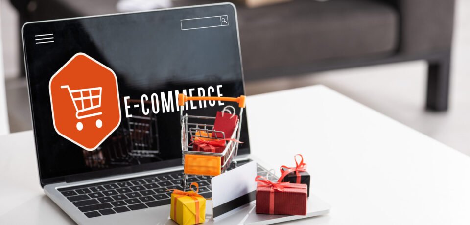 Toy gift boxes and credit card on laptop with e-commerce lettering on table