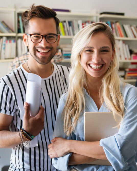 Young manager talking with experienced colleague while using computer in office. Colleagues discuss business, financial and marketing projects. Specialists work in diverse startup team.