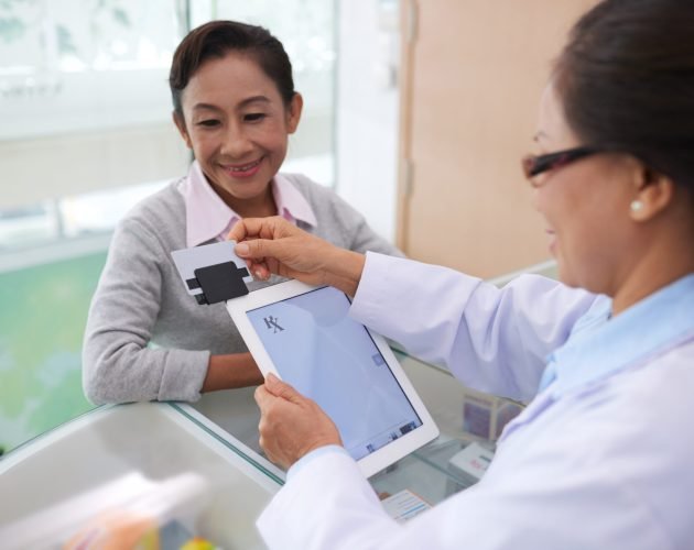 Pharmacist using credit card reader and digital tablet when accepting payment