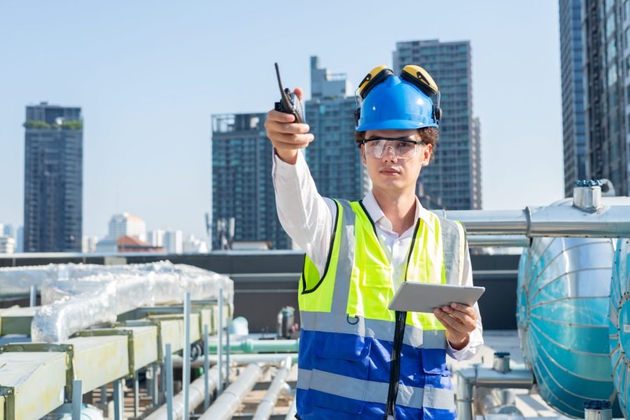 Engineer inspects water heater pump system and hot water tank on industrial roof