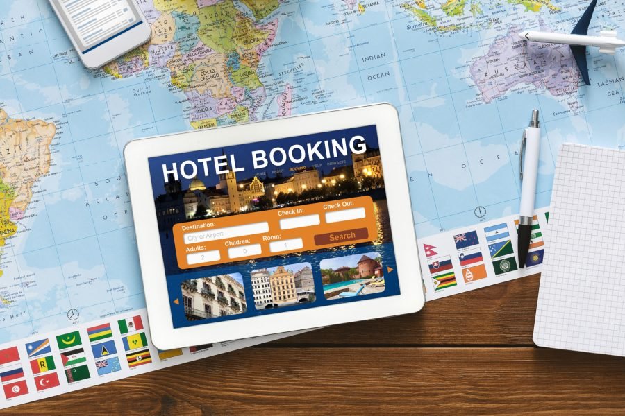 Hotel Booking Background. Digital Tablet With Application For Travel Accommodation Search Lying On Desk With Travel Map. Collage, Above View